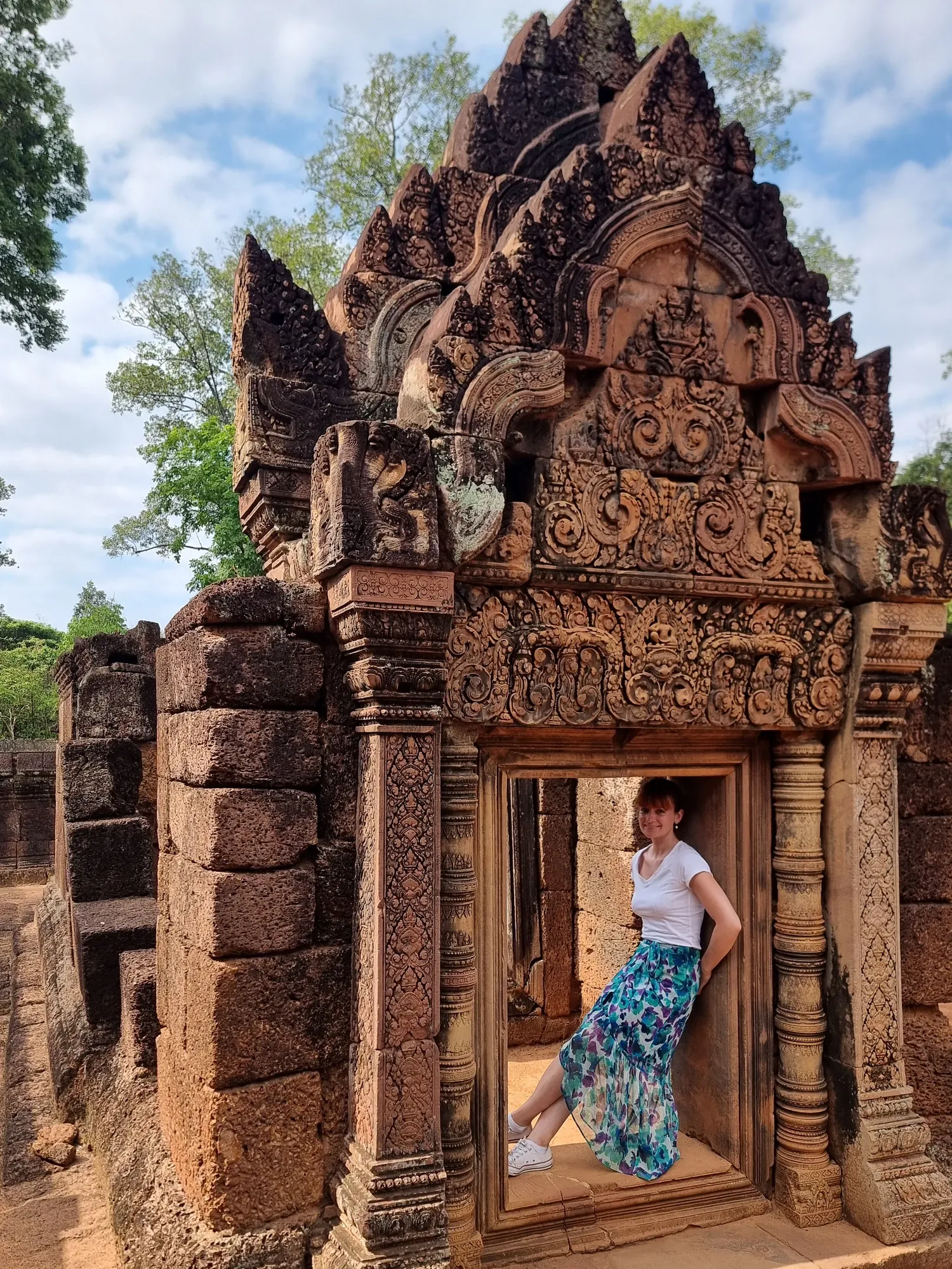 Ségolène, adossée dans l'encadrement d'une porte de Banteay Srei, sous un fronton de grès rose sculpté