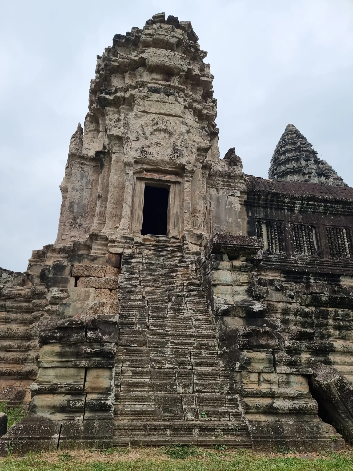 Une tour d'Angkor Wat et son escalier de pierre très raide, sous un ciel couvert