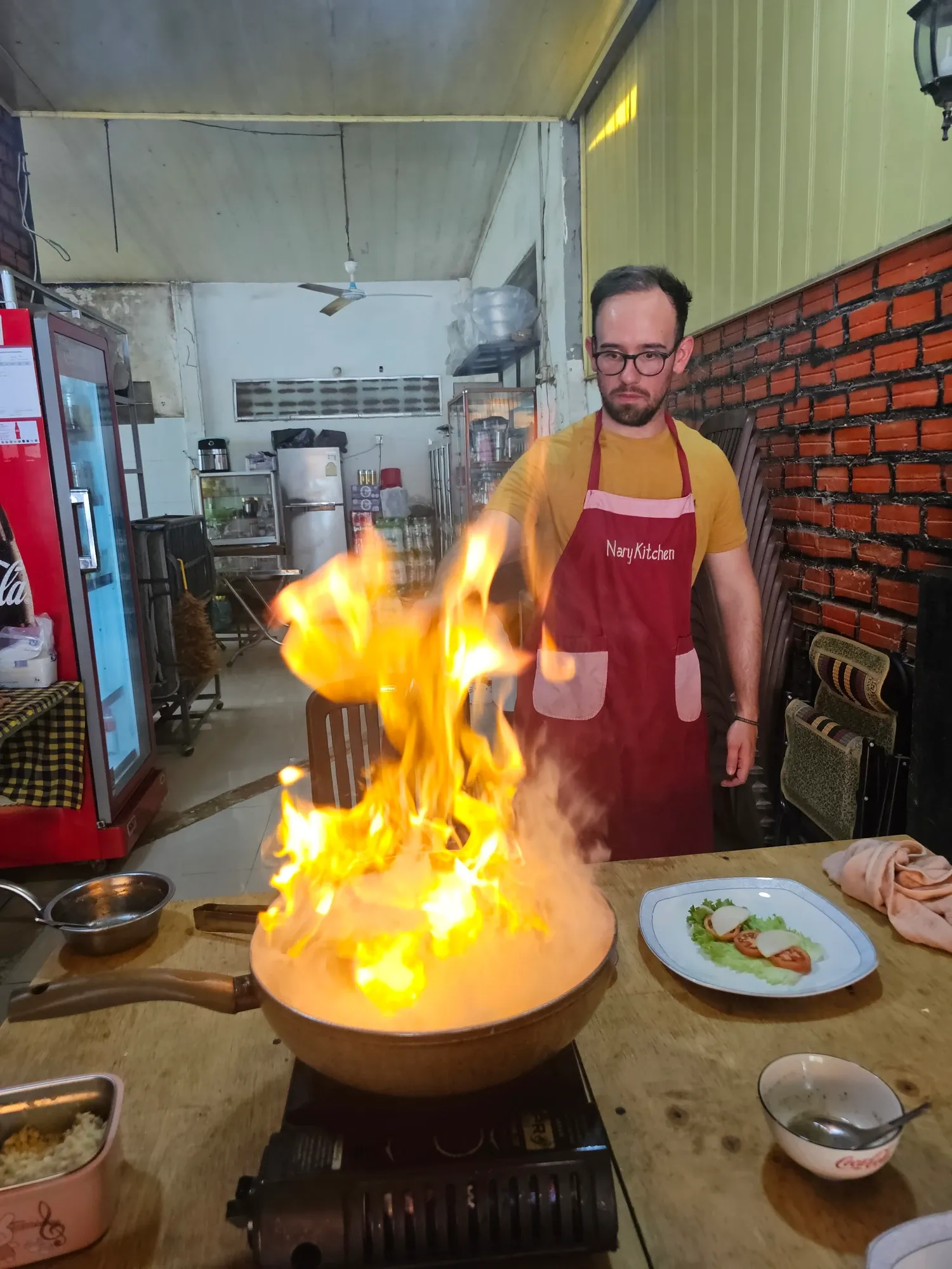 Une grande flamme jaillit de la poêle devant Antoine, au poste de cuisson