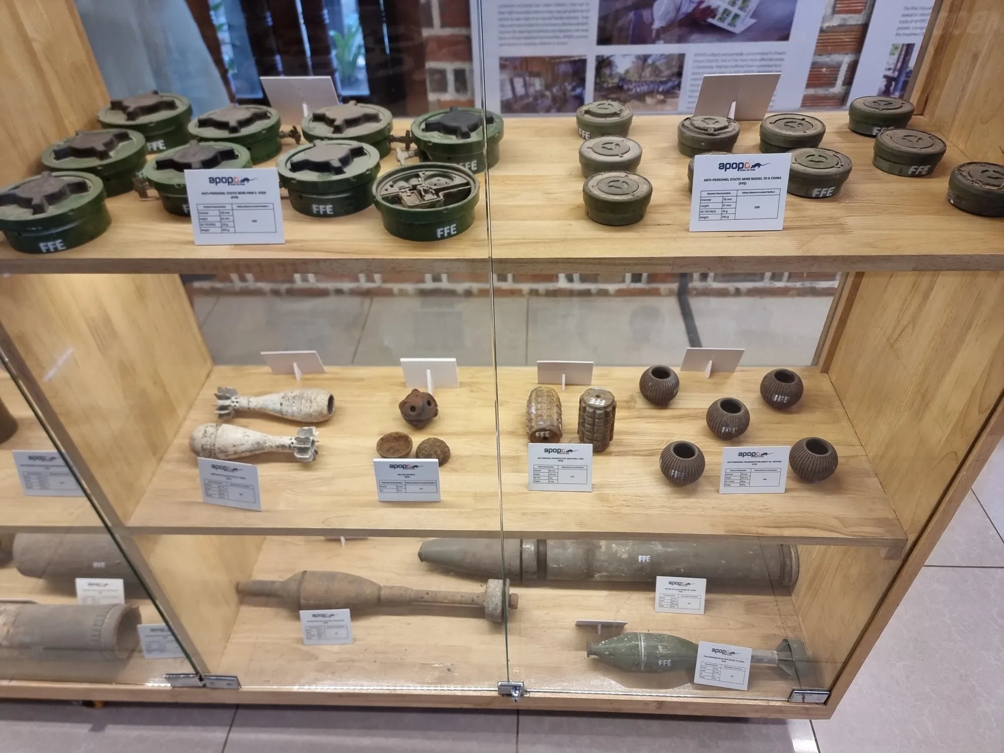 Vitrine de l'Apopo Center remplie de mines désamorcées, d'obus et de grenades, chacun accompagné de son étiquette