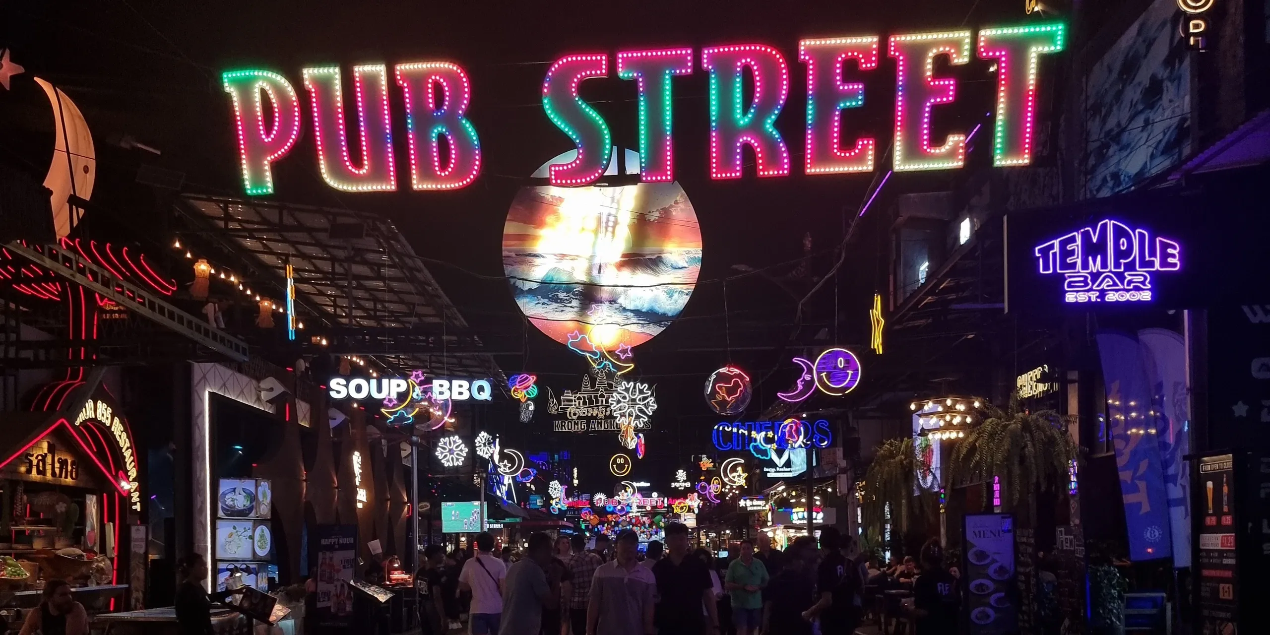Enseigne lumineuse Pub Street en néons multicolores au-dessus d'une rue piétonne animée de Siem Reap, de nuit, entre les façades éclairées des bars et des restaurants, au Cambodge